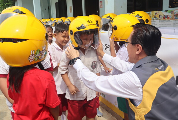 안전모 전달식에 참여한 KB손해보험 조정래 인니법인장이 Sinar Cahaya Kasih 학교 학생들에게 안전모를 씌워주고 있다.