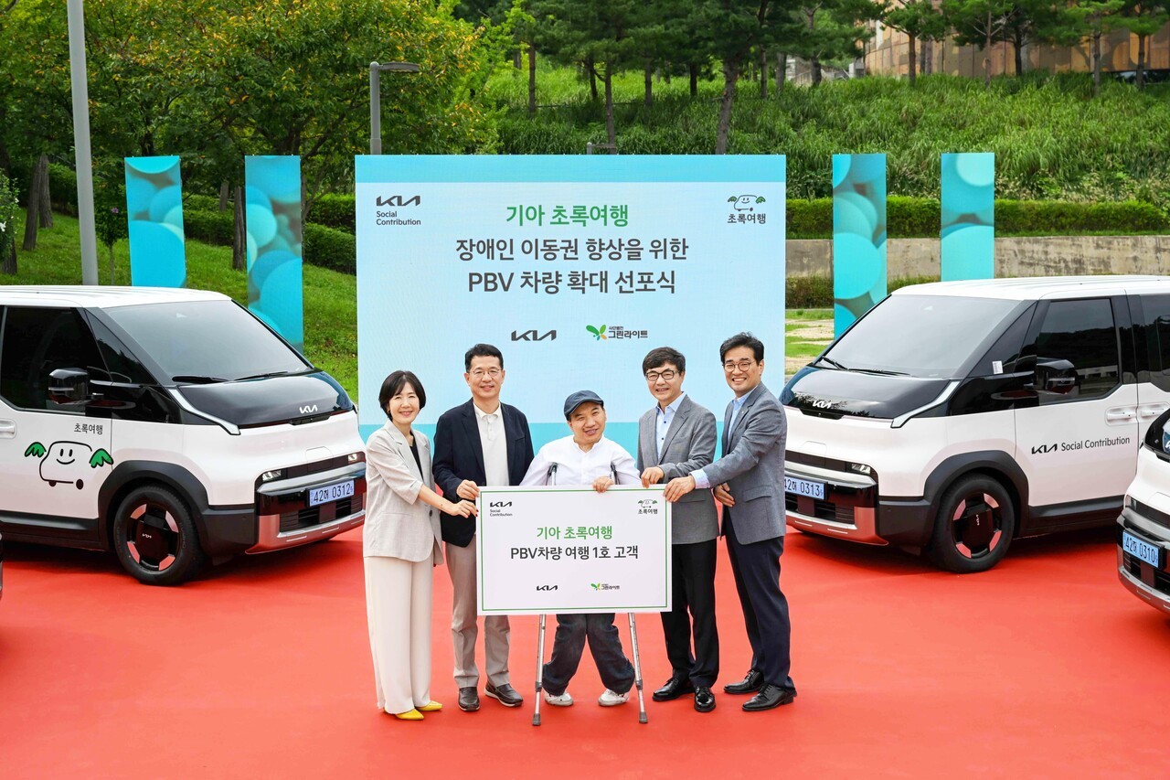 기아 지속가능경영실장 이덕현 상무(왼쪽 두 번째), 사단법인 그린라이트 이재강 회장(왼쪽 네 번째) 등 주요 관계자들이 PV5 여행 1호 고객과 기념 촬영을 하고 있다. 사진=기아