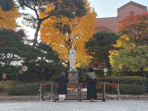 명동성당 내 성모마리아 상 앞에 봉헌초를 올리며 기도 하는 여성들의 뒷모습 사진=뉴시스